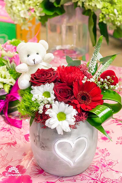 Compos de roses rouges et fleurs blanches dans un pot gris en terre avec un coeur gravé